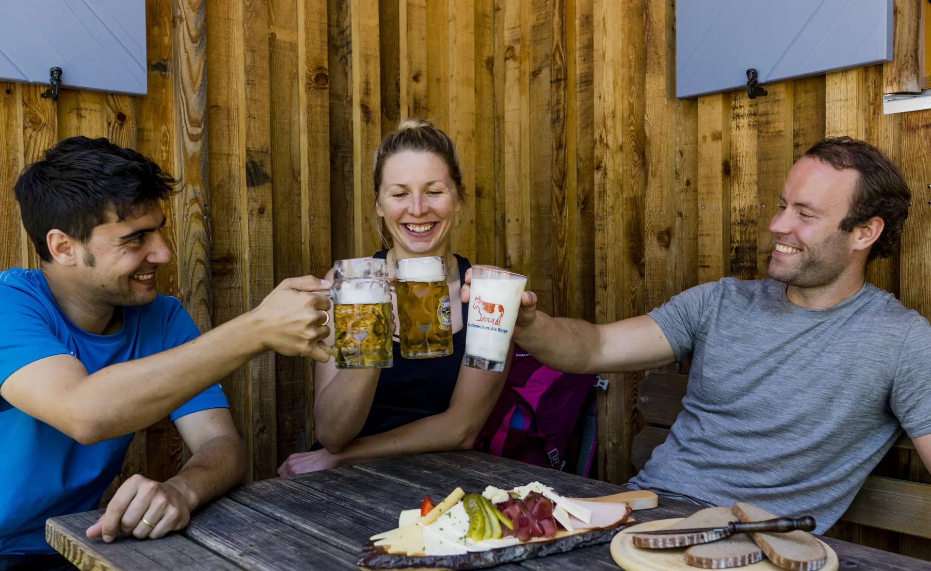 Auf der Hütte: Drei Personen stoßen mit Bierkrügen an | © DAV/Hans Herbig